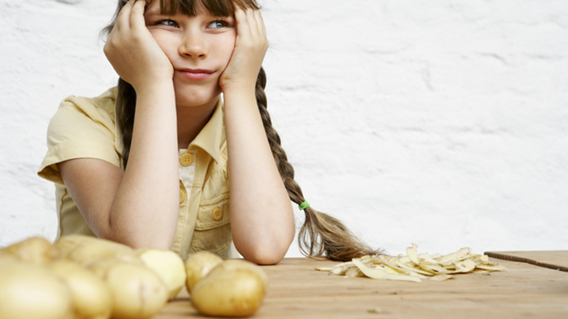 Little Girl Sitting at a Table with Potatoes