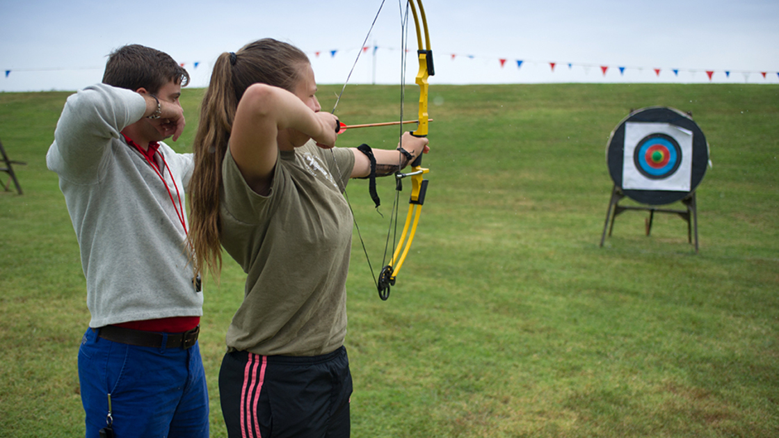 Archery instructor James Brandon teaches Olivia proper stance as she takes aim at the target. 