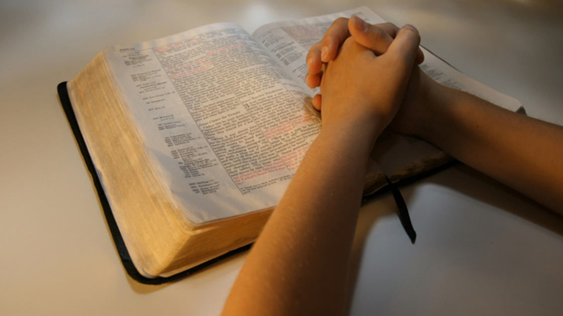 A photo of a person praying over their Bible.