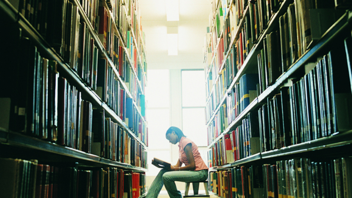Female University Student Reading a Book in a Library