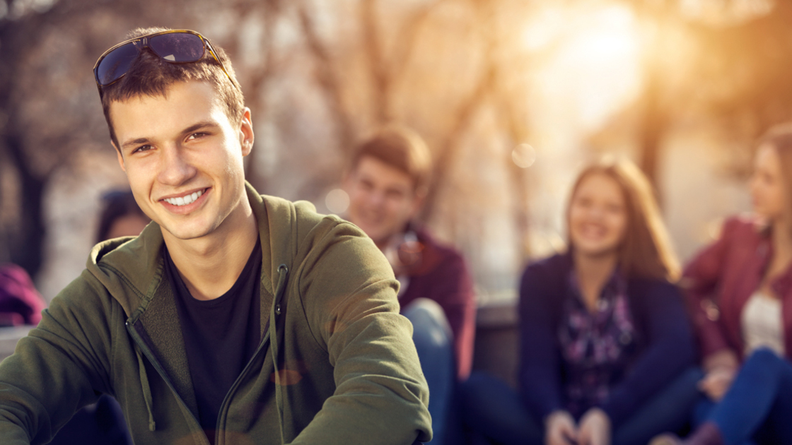16x9(Remember young people)
Portrait of a teenage boy sitting and smiling in front of his friends