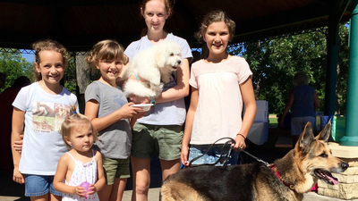 Pictured (L to R): Katelyn Aldrich, Violet Kaleho, Chloe Kaleho, Erica Anderson (holding Ozzie the Dog in her arms), Sofia Kaleho (holding Kaia the dog on a leash).