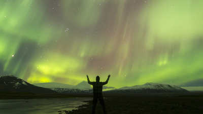 aurora borealis on iceland, human silhouette in foreground, some ISO-noise