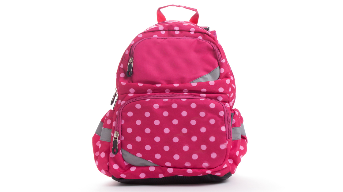 Pink school backpack with white dots isolated on white.